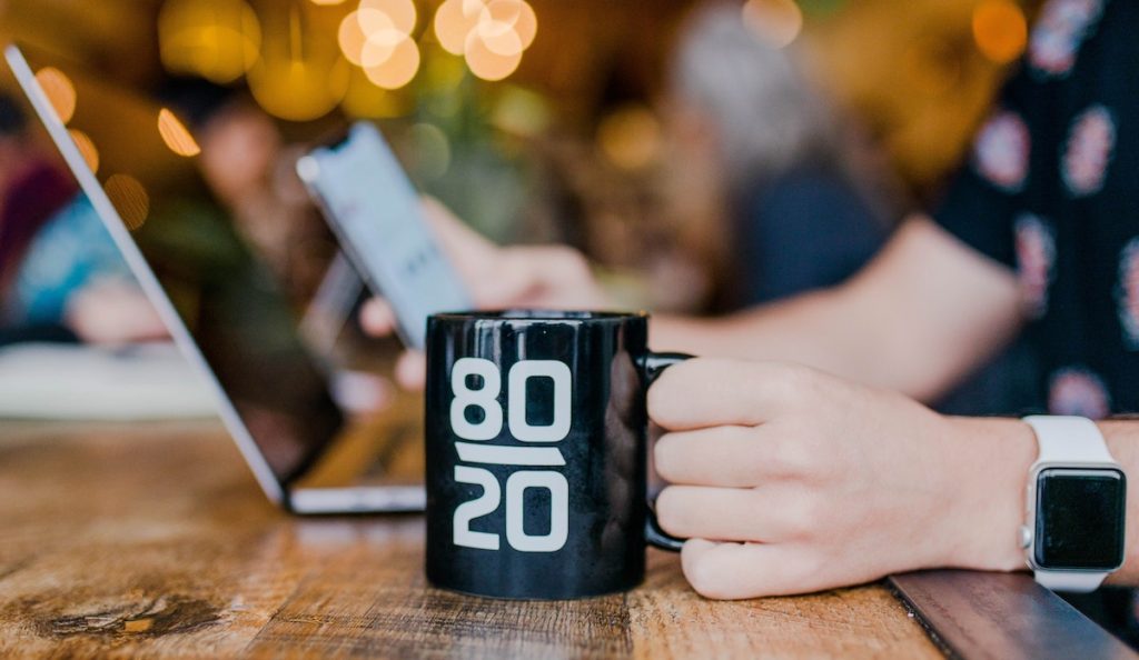 image of someone holding a coffee mug working on a laptop